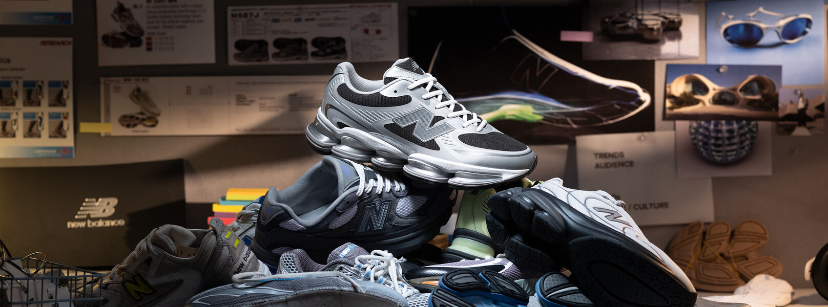 Grey shoes that are unlaced on a table, Infront of a computer monitor. 